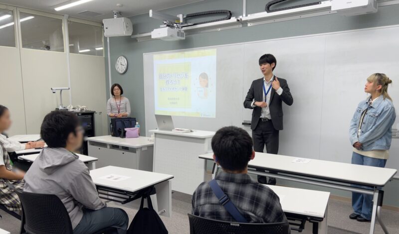 共生社会創成学部の新教室での体験授業の様子。前方に教員2名とスタッフ学生1名が立ち、授業に参加する生徒さんが4名着席している。